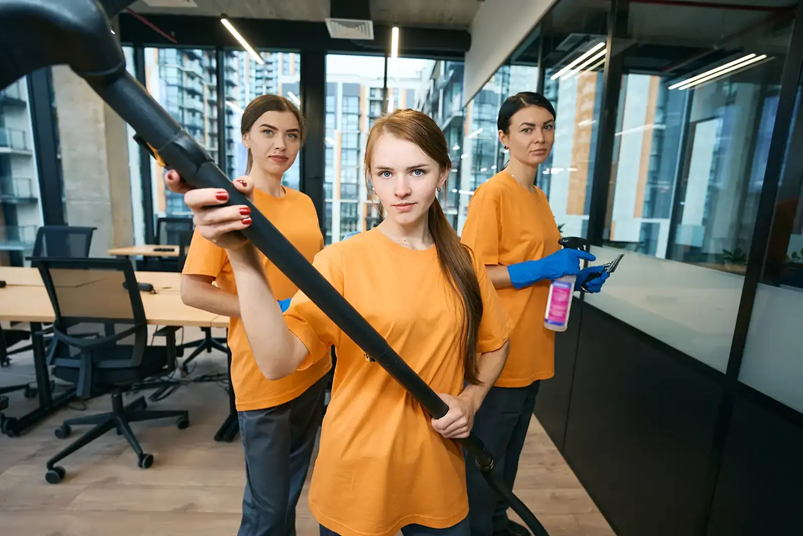 Schoonmakers van Bureau Link in oranje shirts aan het werk in een kantoor